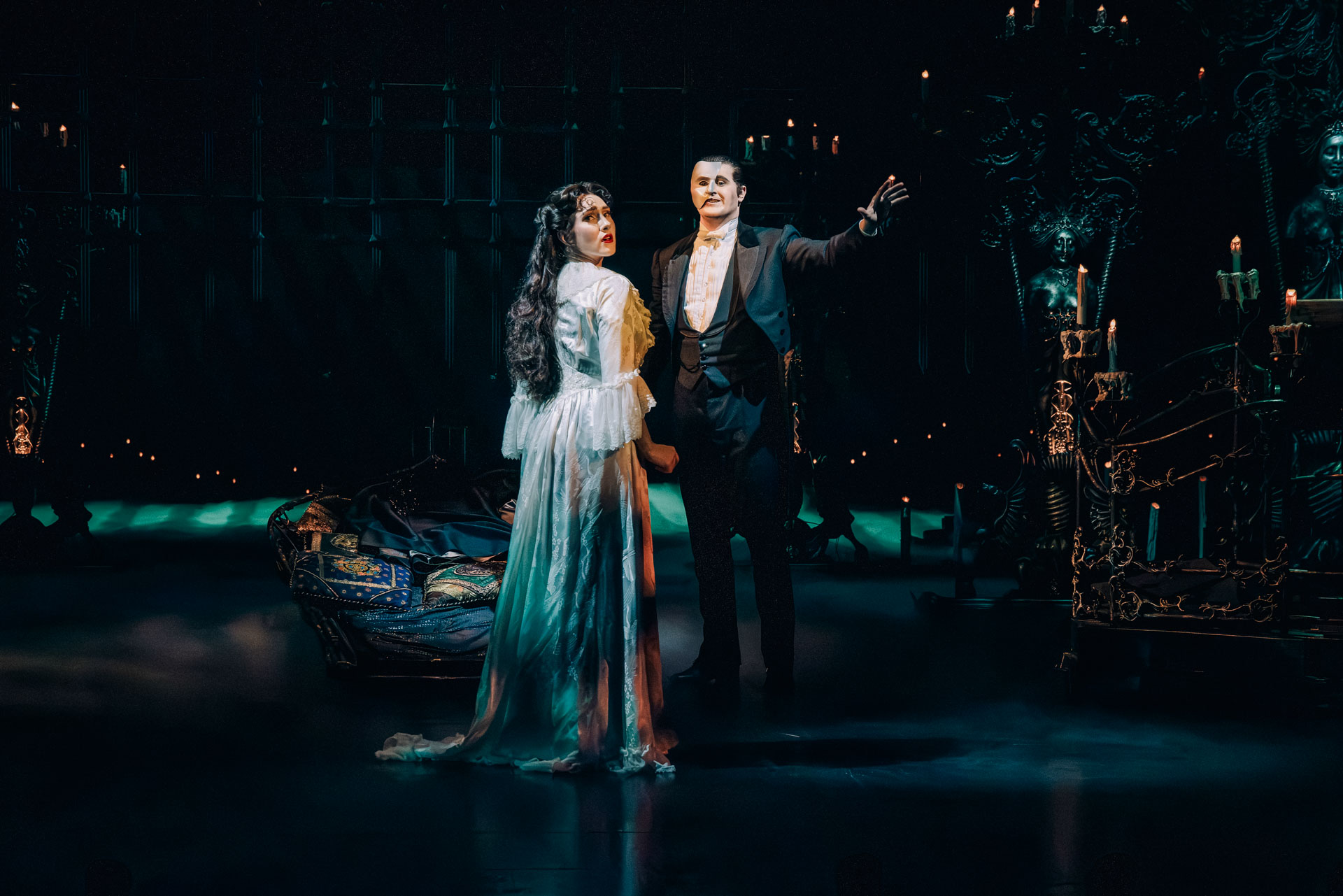 The Phantom and Christine stand together in the candlelit lair beneath the Paris Opera House in a scene from The Phantom of the Opera