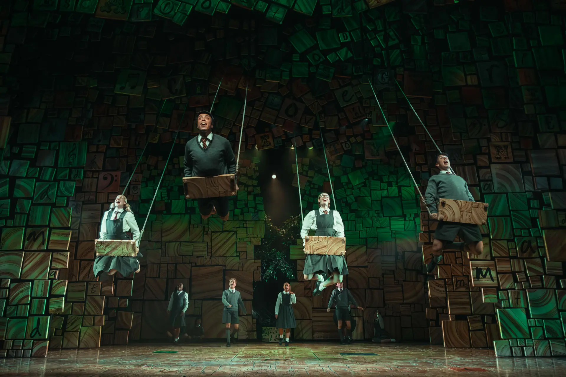 Matilda The Musical international tour – the 'When I Grow Up' scene, with cast members soaring on swings above a stage of alphabet blocks